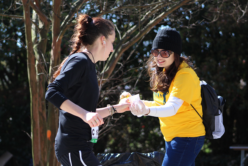 Volunteer handing out water at the Georgia Tech Hydration Station during the Publix Georgia Marathon.