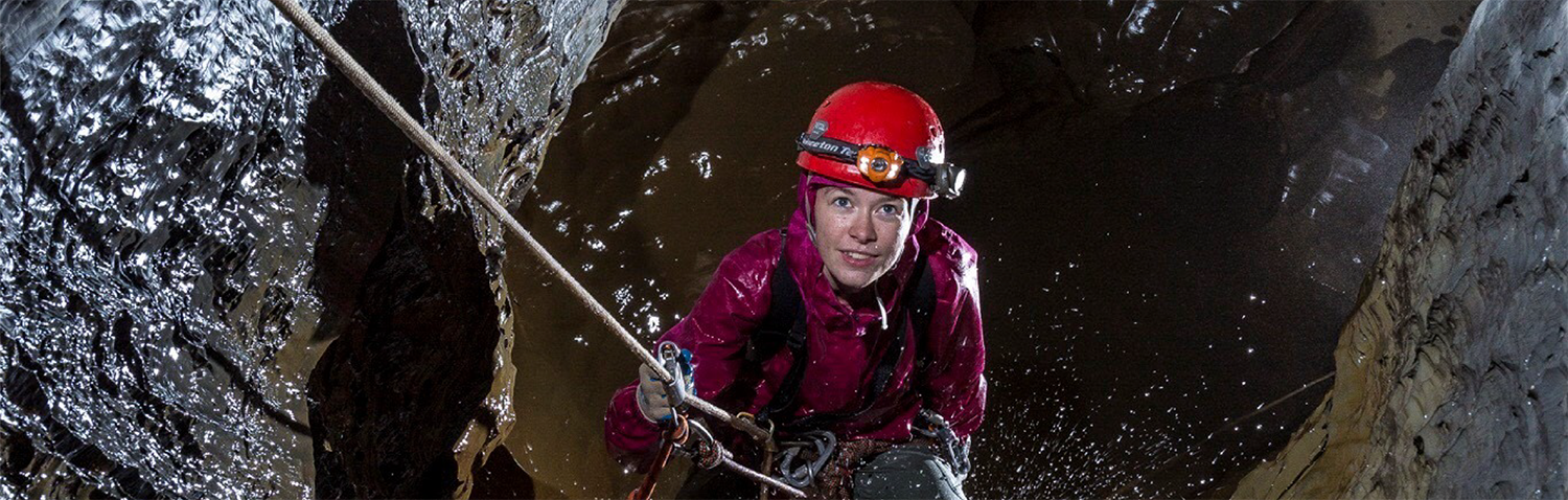 A  young woman rapelling down a cave.
