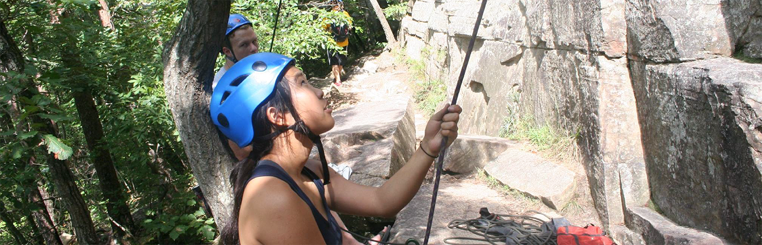 A young woman with a rapel starting to rock climb.