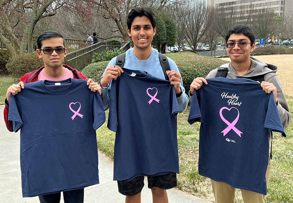 Three young men holding a Healthy Heart T-Shirt.